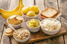 Kitchen table spread for diarrhea and stomachache relief: Bananas, crackers, rice, toast, potatoes, and oats arranged in a soothing display.