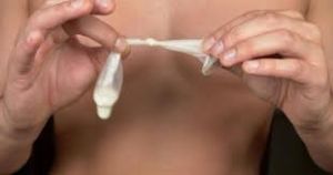 Used condom tied at the open end before disposal in a trash bin.